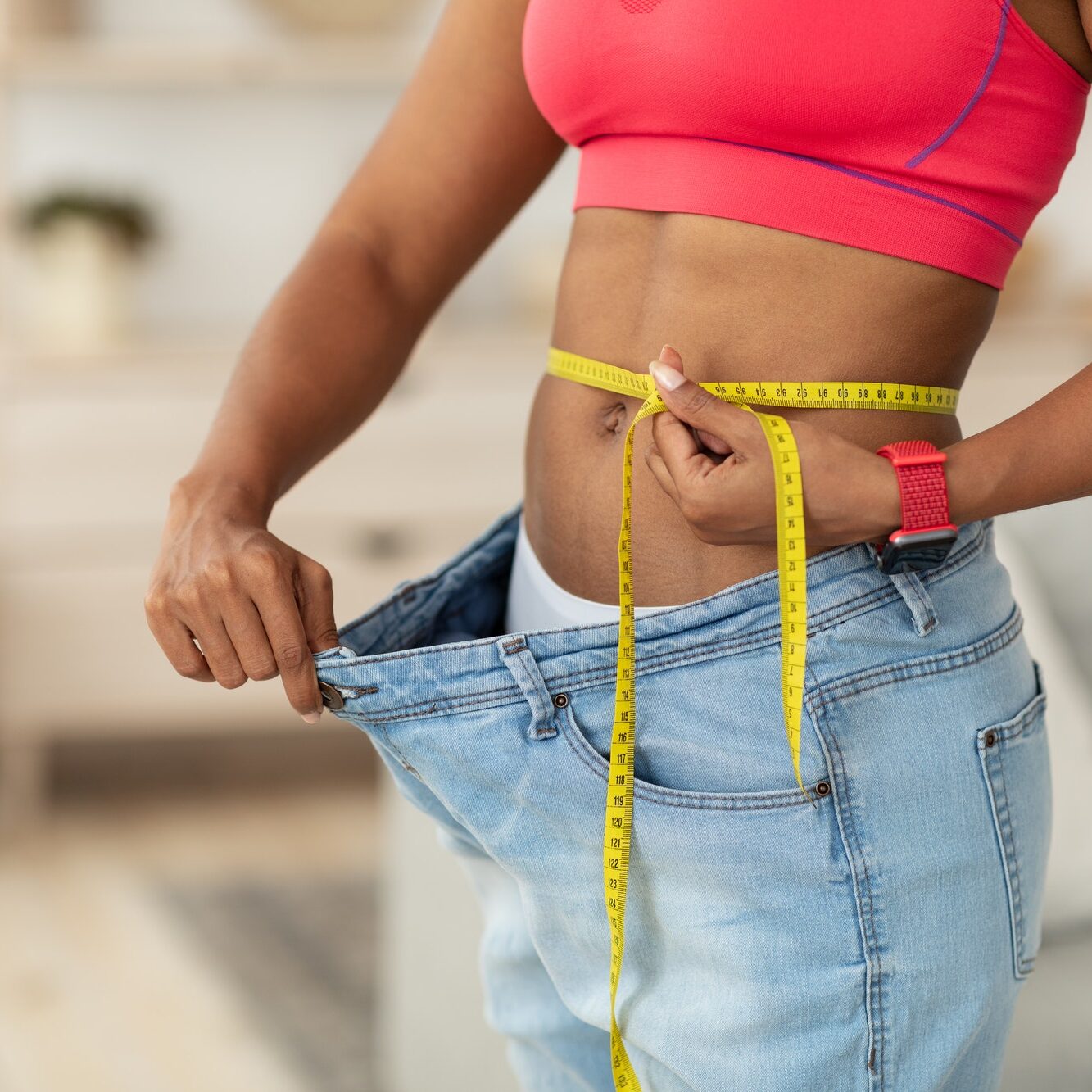 Woman After Weight-Loss Measuring Waist Wearing Oversize Jeans Indoors, Cropped